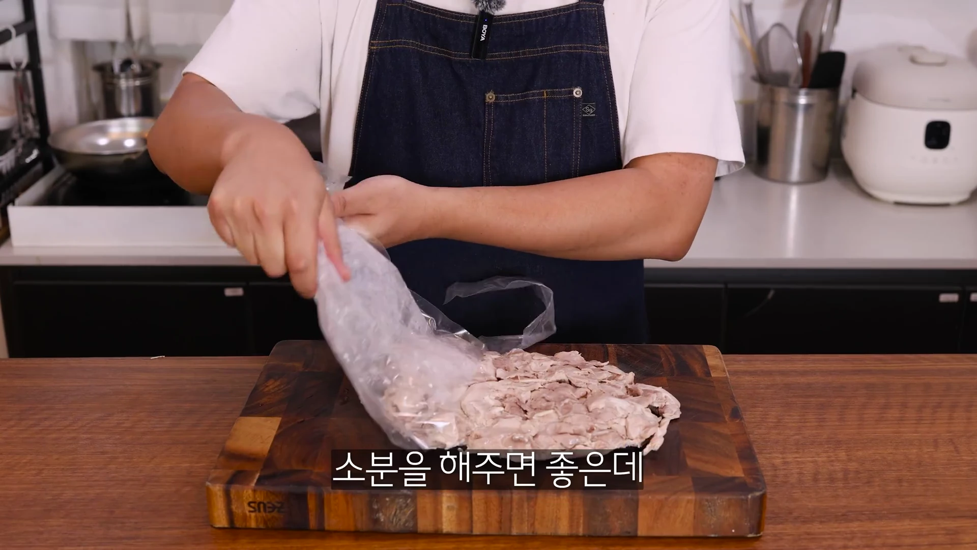 앞치마를 두른 요리사가 도마 위에서 삶은 사태 고기를 비닐봉지에 담아 소분하고 있다.