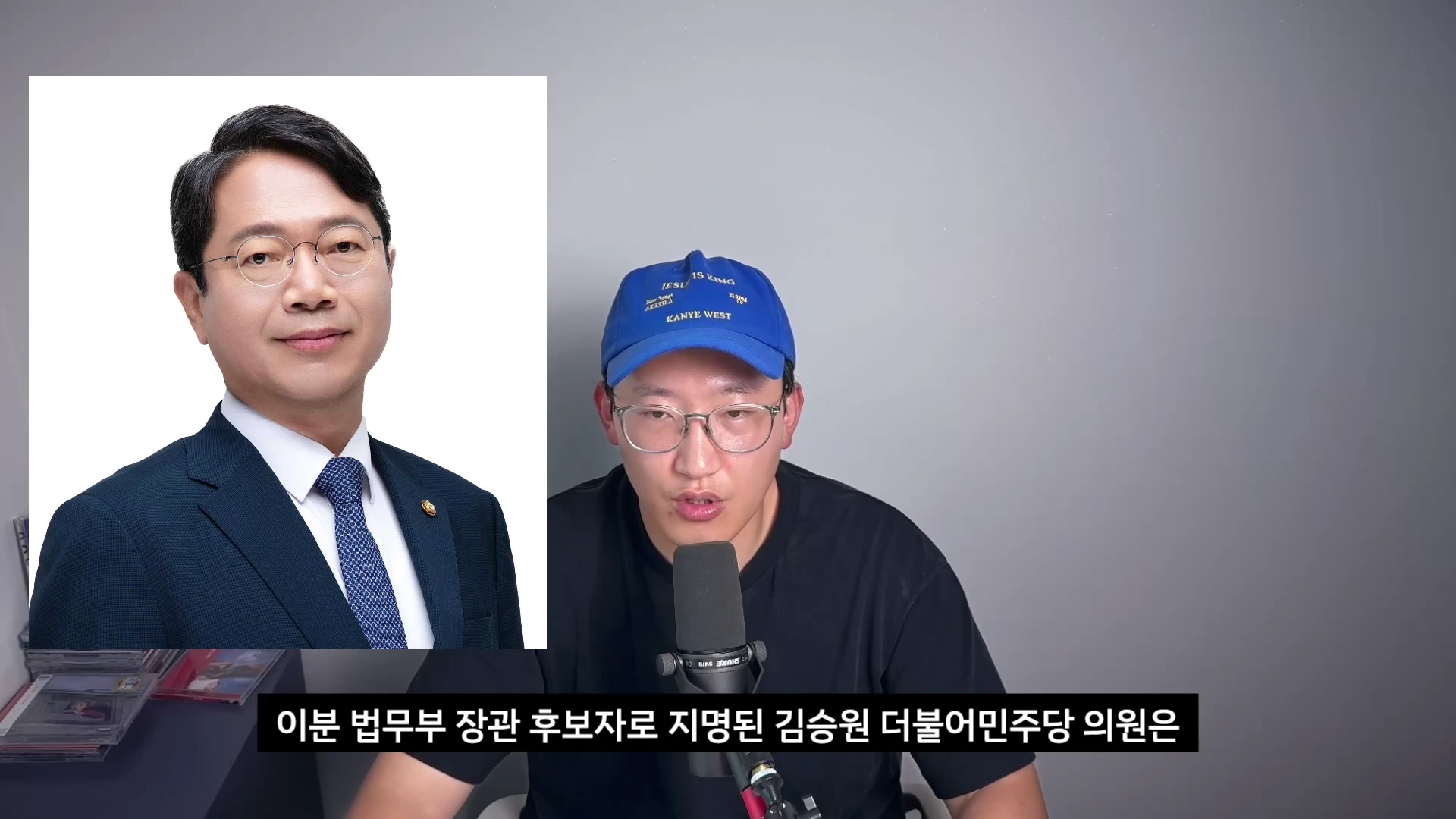 파란색 모자를 쓴 남성이 마이크 앞에서 이야기하고 있고, 화면 왼쪽에는 정장을 입고 안경을 쓴 남성의 증명사진이 배치되어 있습니다.