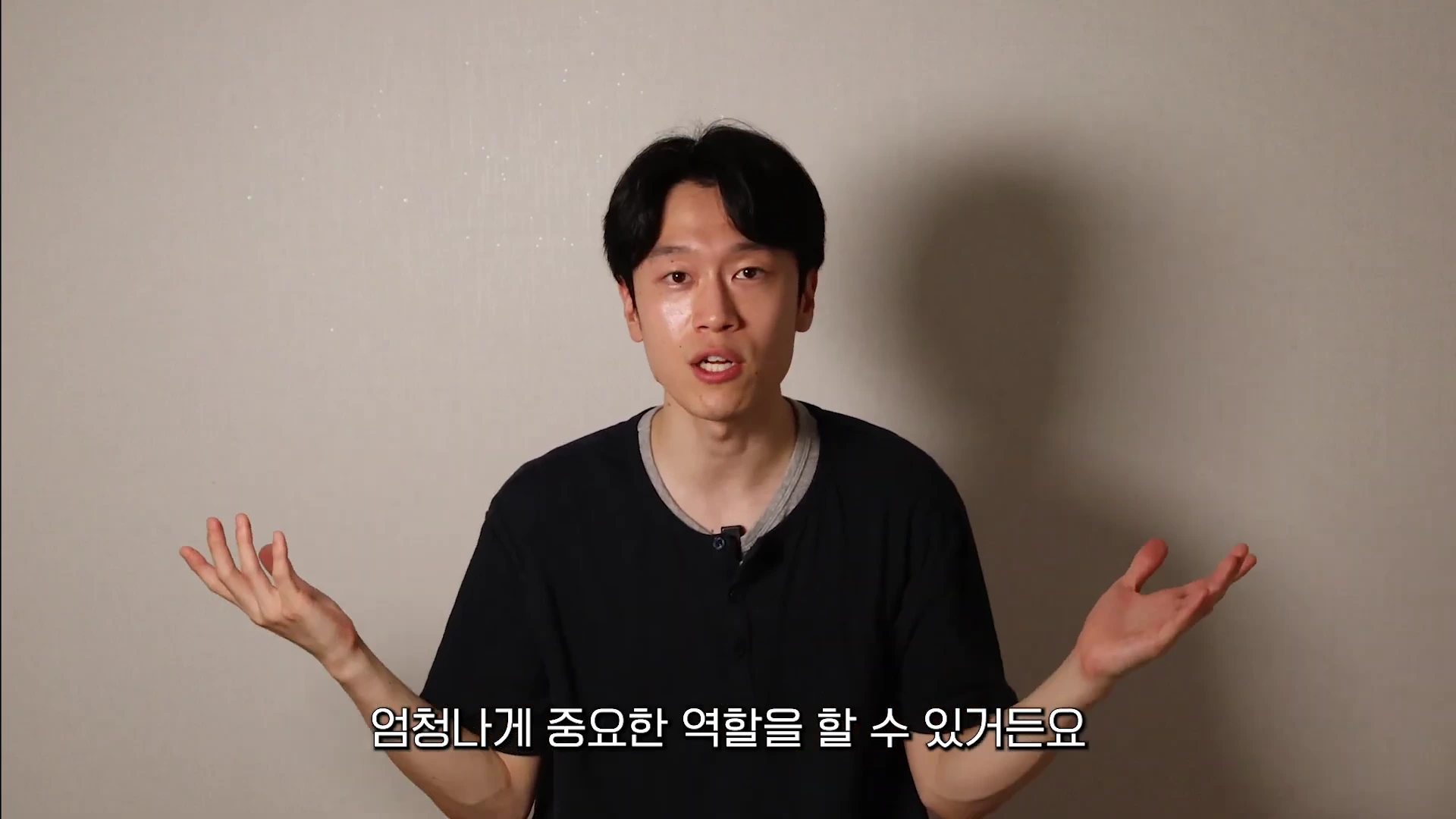 검은색 티셔츠를 입은 남성이 양손을 펼치며 설명하고 있는 영상 캡처 화면이며, 화면 하단에는 한국어 자막이 표시되어 있습니다.