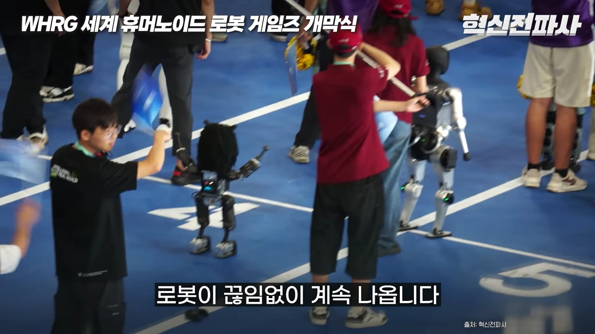 실내 경기장 트랙 위에서 여러 대의 휴머노이드 로봇이 사람들과 함께 입장식을 진행하는 모습으로, 화면 상단에 'WHRG 세계 휴머노이드 로봇 게임즈 개막식'이라는 문구와 하단에 '로봇이 끊임없이 계속 나옵니다'라는 자막이 표시되어 있습니다.