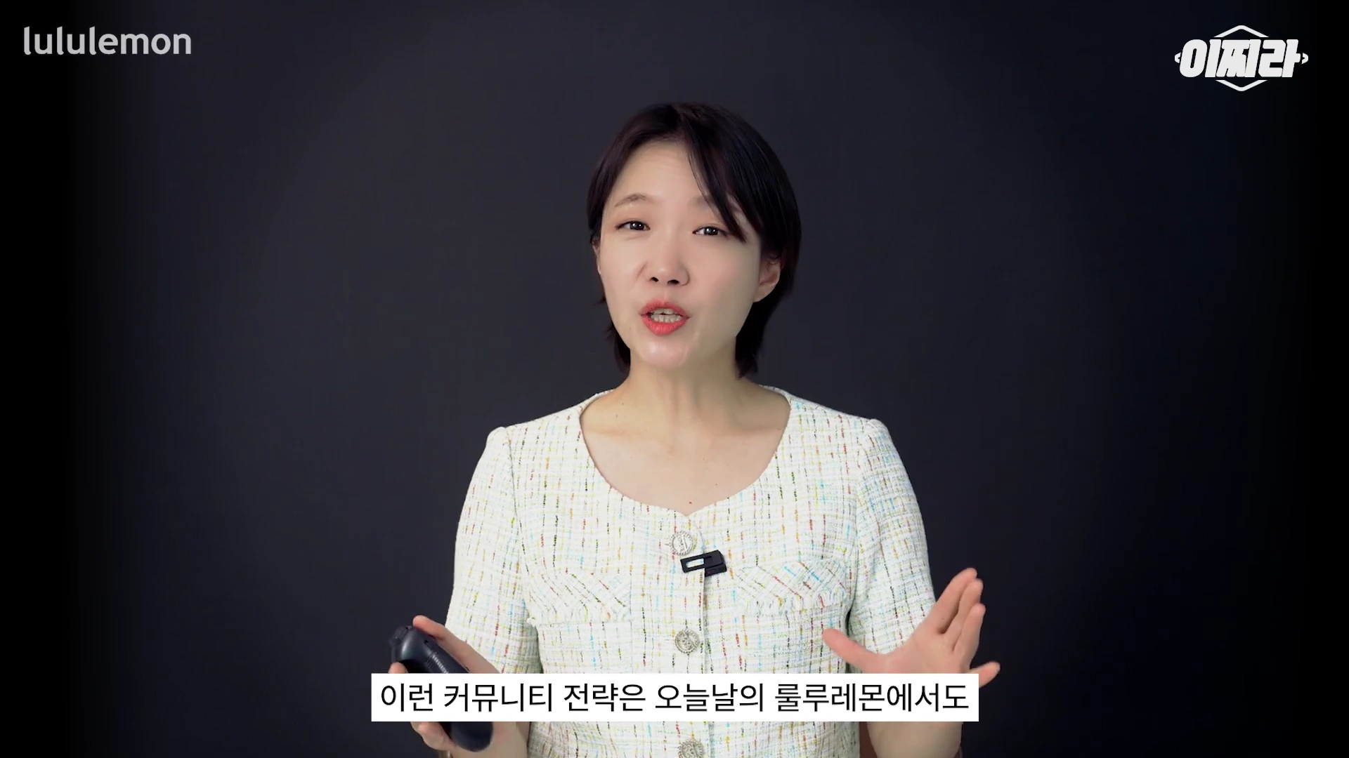 단발머리를 한 여성이 어두운 배경 앞에서 제스처를 하며 이야기를 하고 있으며 화면 하단에는 자막이 떠 있습니다.