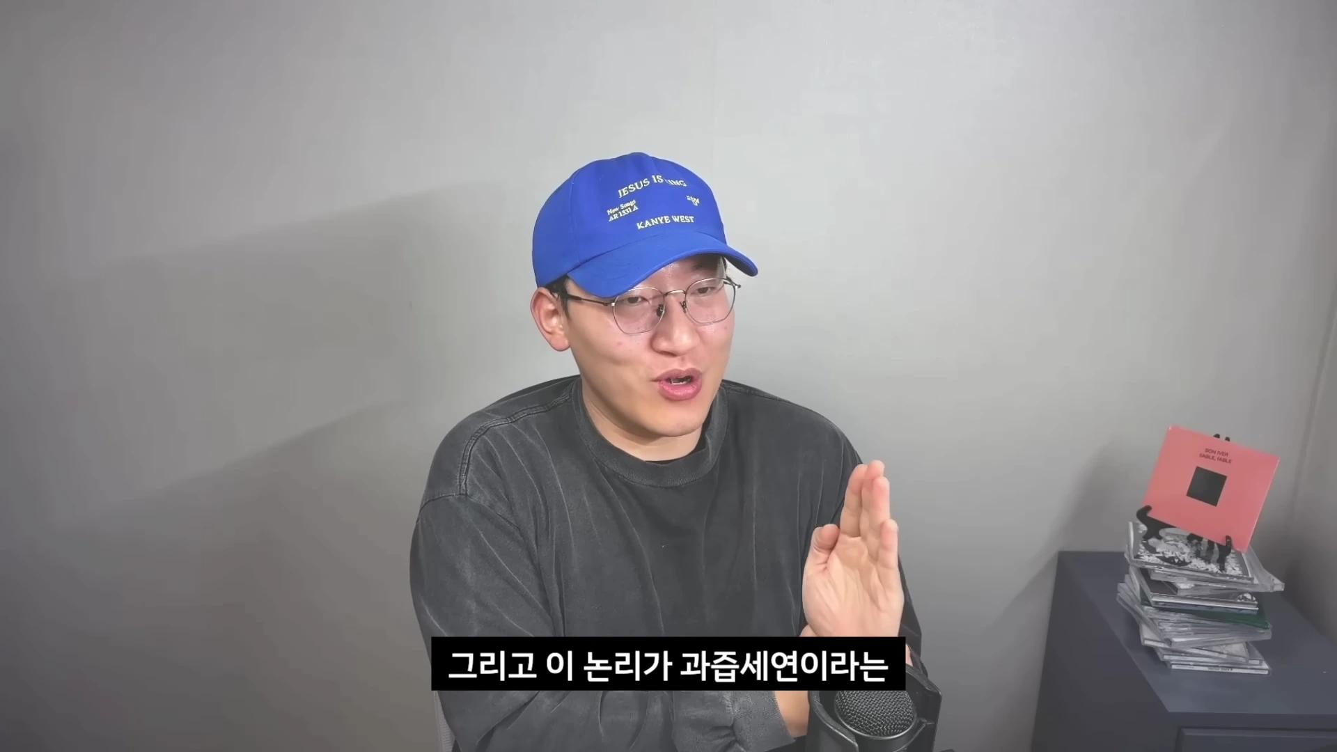 파란색 야구 모자를 쓰고 안경을 쓴 남성이 회색 배경 앞에서 마이크를 앞에 두고 이야기를 나누고 있는 모습이다. 화면 하단에는 '그리고 이 논리가 과즙세연이라는'이라는 자막이 적혀 있다.