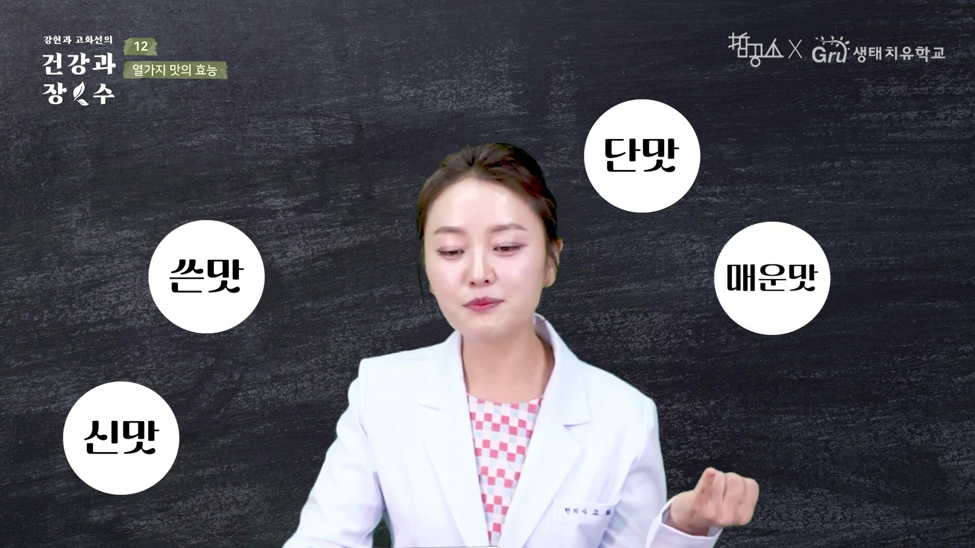 흰 가운을 입은 여성이 검은 칠판을 배경으로 서 있고, 그 주변으로 단맛, 매운맛, 쓴맛, 신맛이 적힌 흰색 원형 그래픽이 떠 있는 영상 장면입니다.