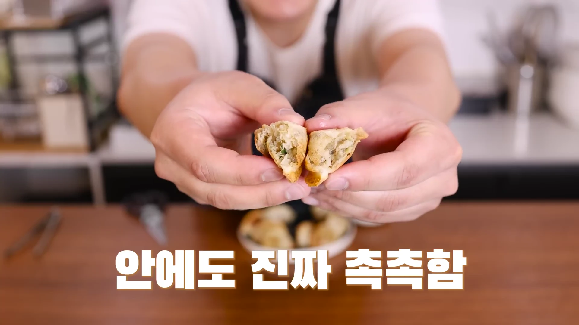 두 손으로 반으로 가른 군만두의 속살을 카메라 정면으로 들어 보이고 있는 모습이다.
