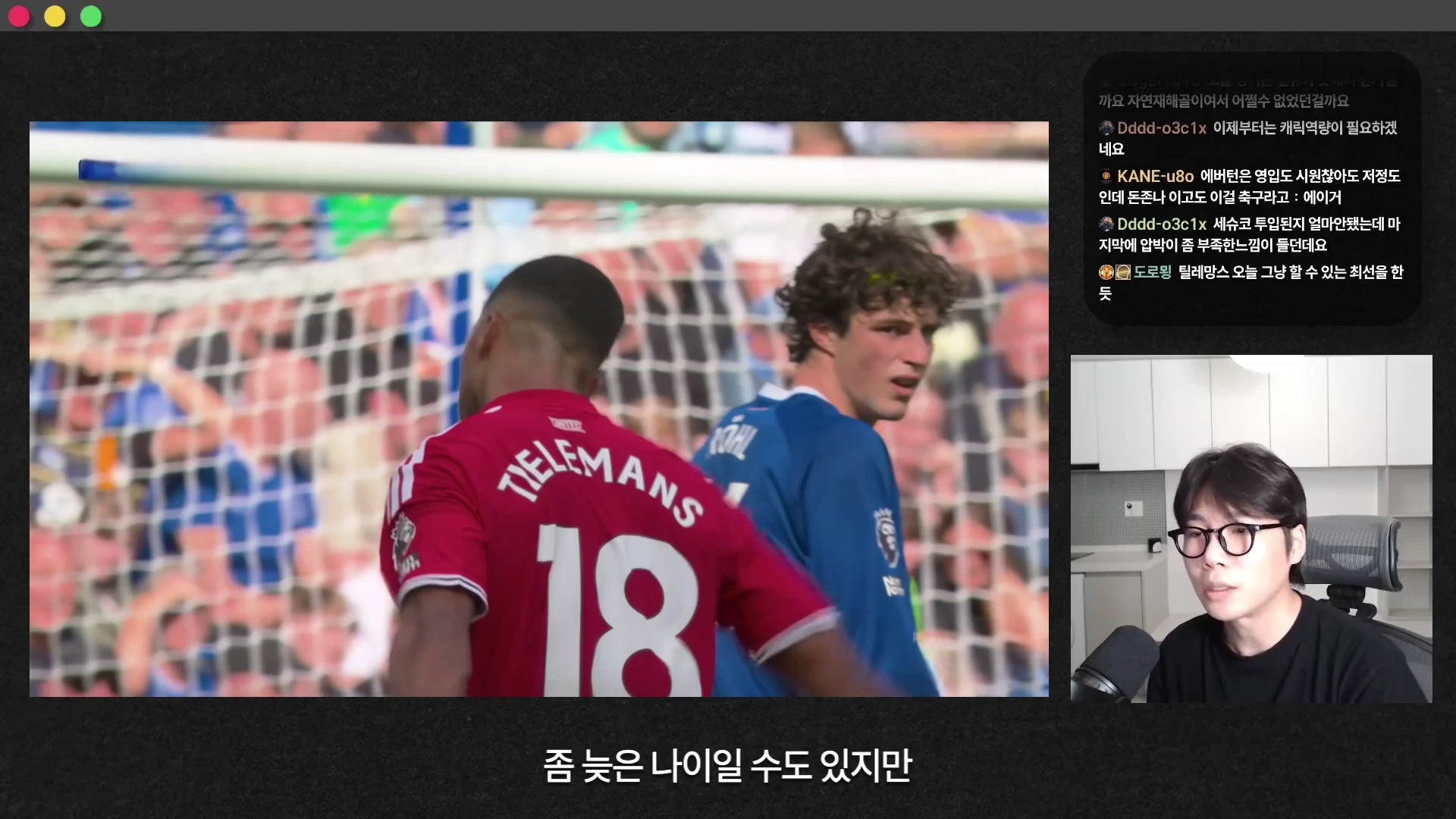 축구 경기 영상과 이를 분석하는 남성이 포함된 화면으로, 왼쪽에는 빨간색 유니폼을 입은 18번 선수와 파란색 유니폼을 입은 선수가 경기장에서 나란히 서 있고 오른쪽에는 안경을 쓴 남성이 마이크 앞에서 이야기하고 있습니다.