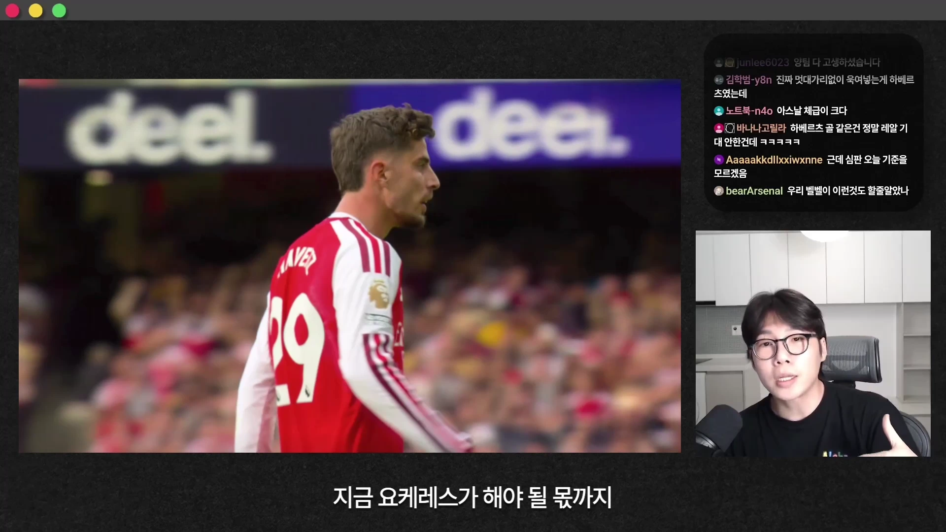 축구 경기 영상이 재생되는 화면 오른편에는 검은 티셔츠를 입고 안경을 쓴 남성이 마이크를 앞에 두고 이야기를 나누고 있으며, 화면 왼쪽에는 아스날 유니폼을 입은 선수가 그라운드를 걷고 있는 모습이 담겨 있습니다.