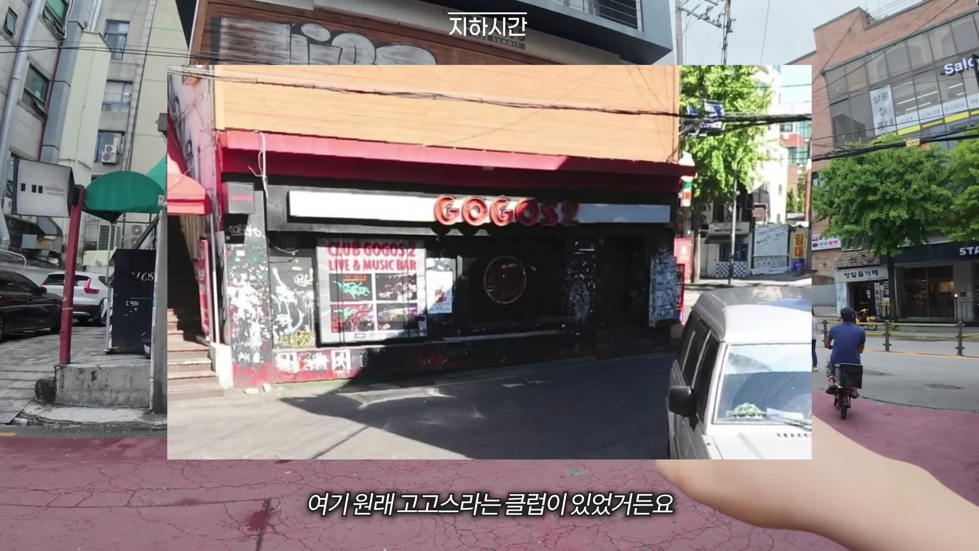 홍대 거리의 낡은 건물 외벽에 'GOGOS2'라고 적힌 라이브 클럽 간판이 붙어 있고, 주변에는 오토바이를 탄 사람과 주차된 차량이 보인다.