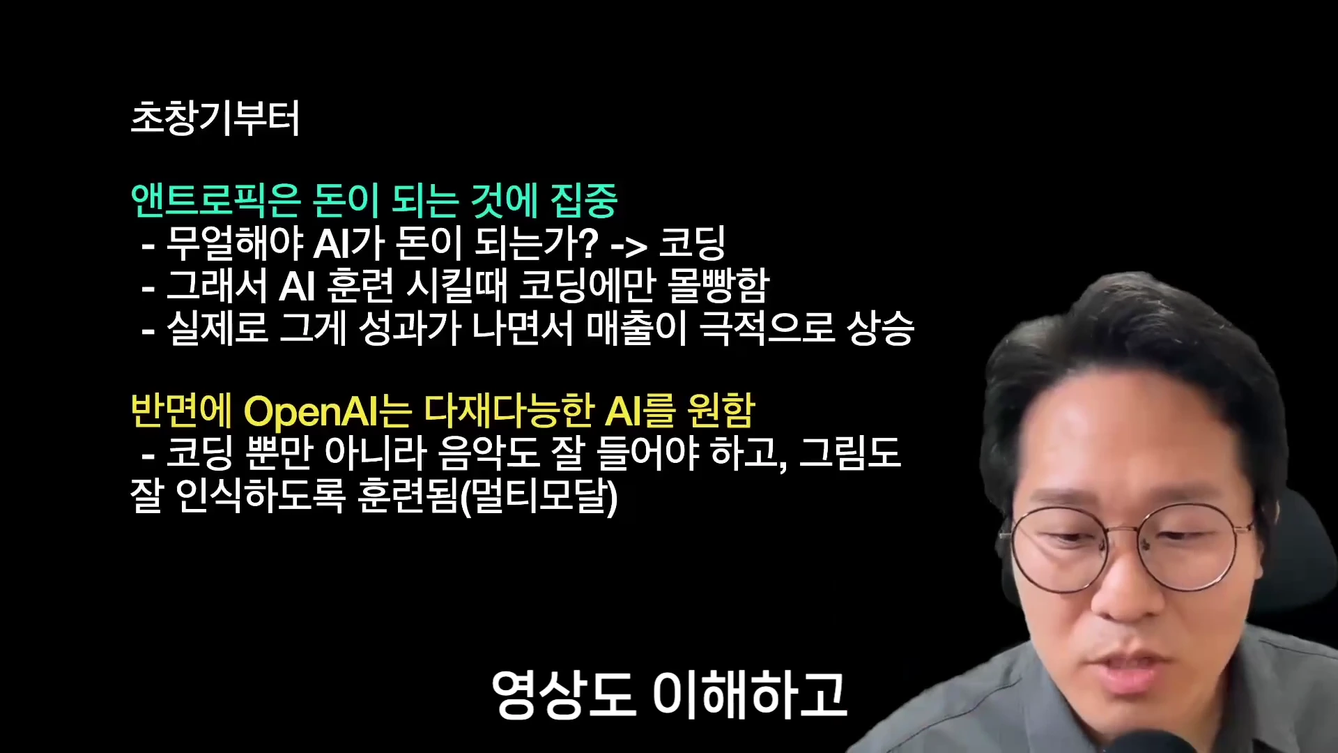 안경을 쓴 남성이 마이크 앞에서 발표하는 영상의 오른쪽 하단에 자리하고, 화면 왼쪽에는 '앤트로픽은 돈이 되는 것에 집중', '오픈AI는 다재다능한 AI를 원함'이라는 요약 텍스트가 배치된 정보 전달 화면.