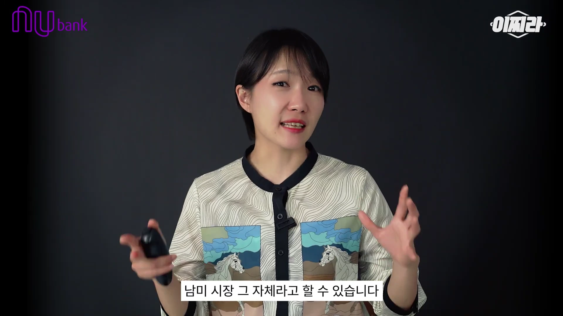 단발머리의 여성 발표자가 어두운 배경 앞에서 손동작을 하며 발표하고 있으며 하단에 '남미 시장 그 자체라고 할 수 있습니다'라는 자막이 표시된 영상 프레임입니다.