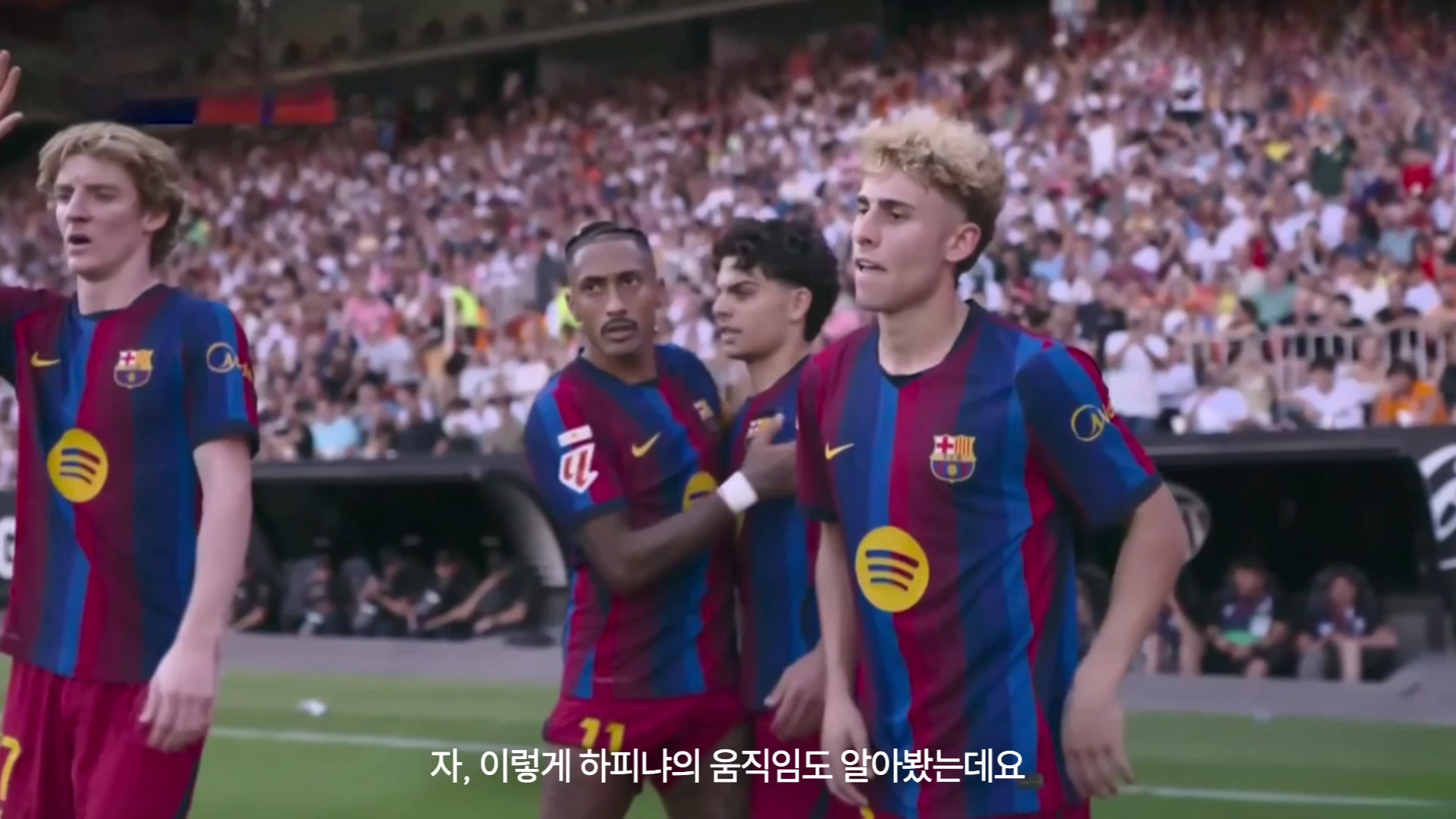 바르셀로나 유니폼을 입은 네 명의 축구 선수들이 경기장에서 경기를 지켜보고 있는 모습이다.