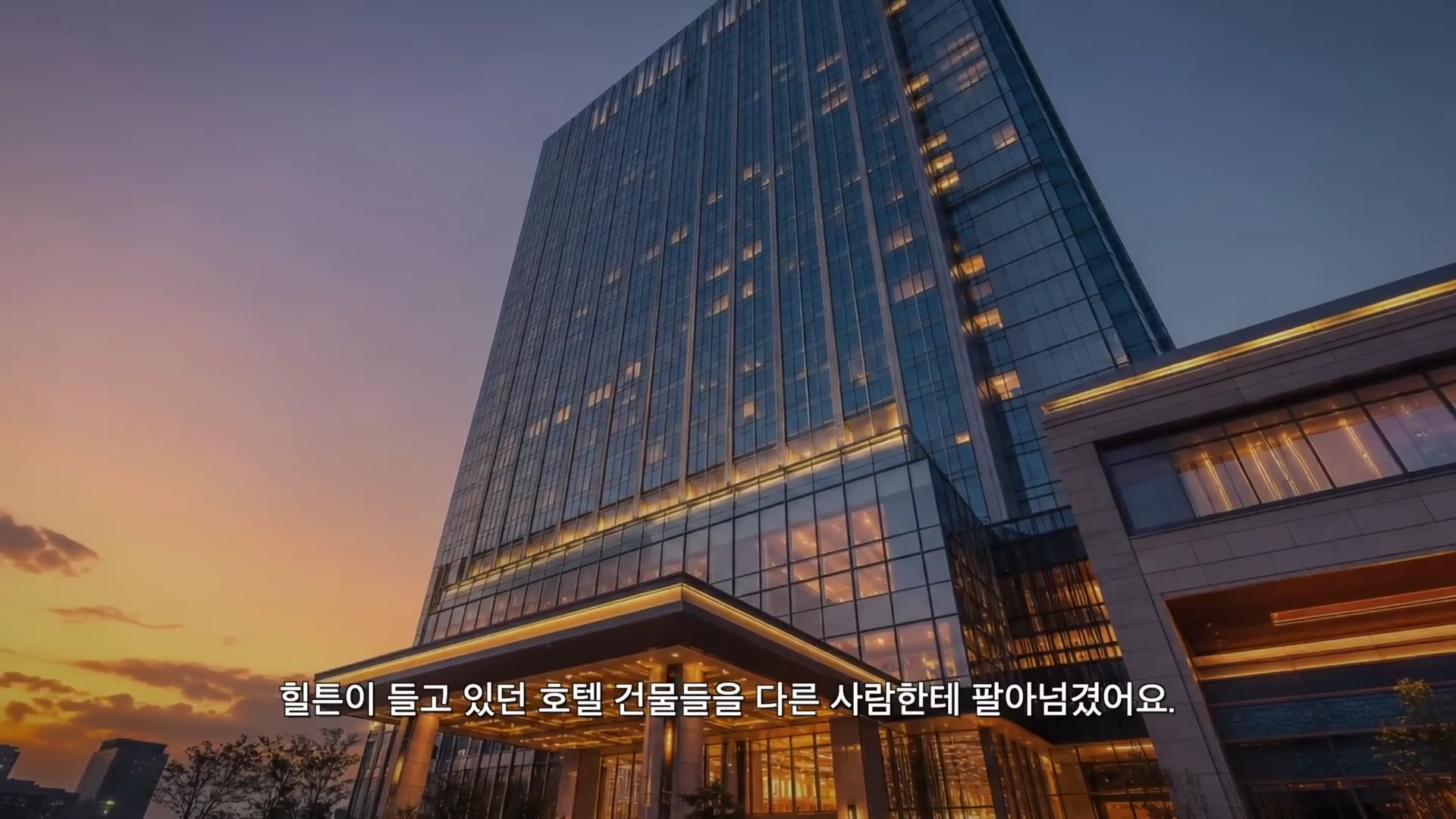 노을이 지는 하늘 아래 불이 켜진 현대적인 고층 호텔 건물의 외관 모습.