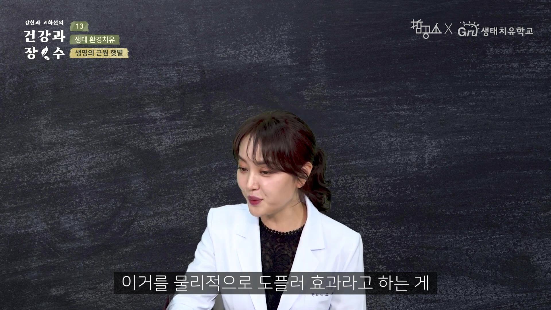 흰색 재킷을 입은 여성이 검은색 칠판 배경 앞에서 이야기를 나누고 있으며, 화면 하단에는 강의 자막이 표시되어 있습니다.