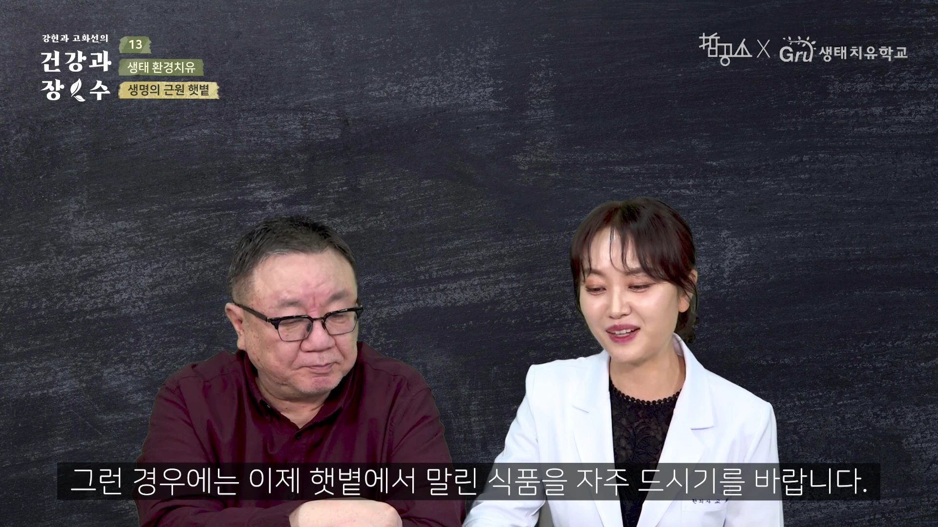 두 명의 진행자가 어두운 배경 앞에서 대화를 나누고 있으며, 하단에는 한국어 자막이 표시된 영상 캡처 화면입니다.