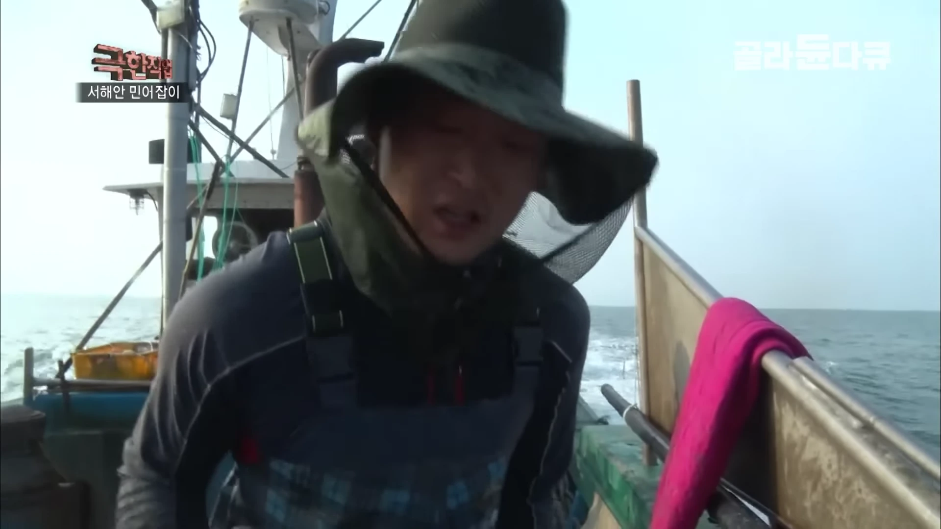 바다 위 배에서 작업 중인 모자를 쓴 어부의 상반신 모습.