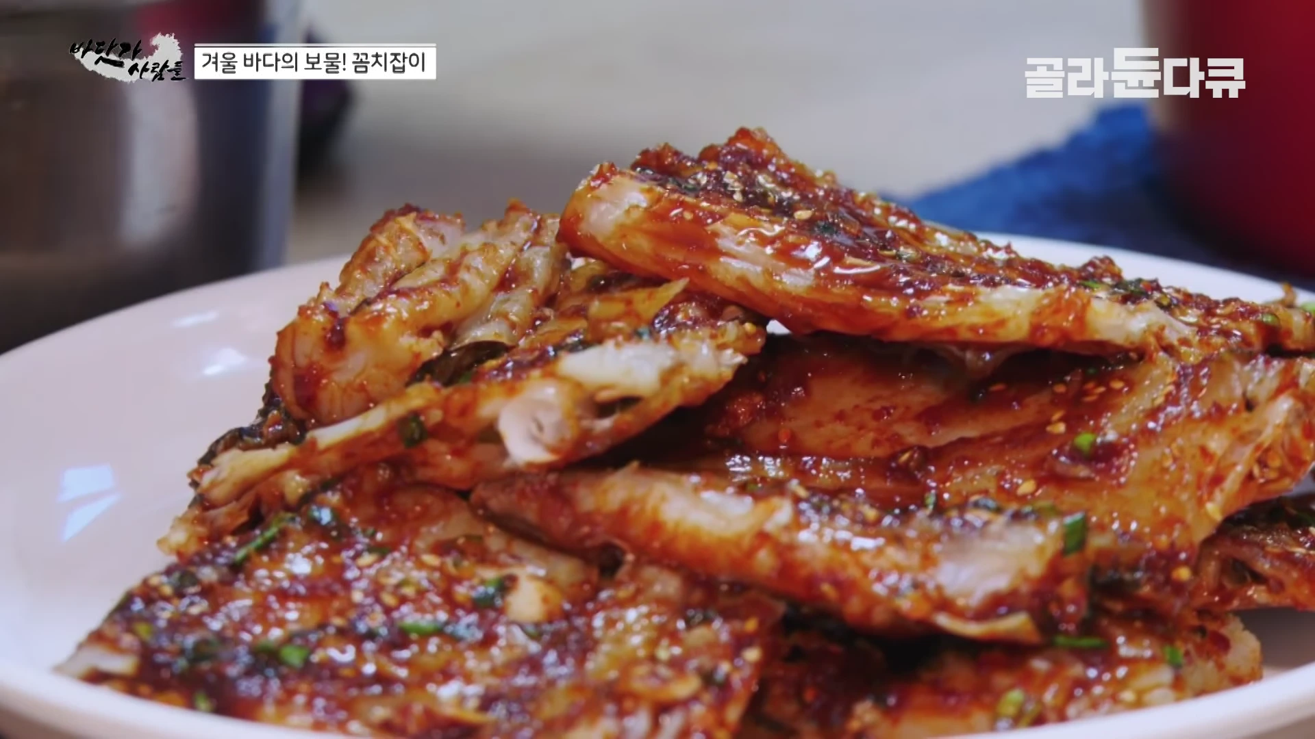흰 접시 위에 붉은 양념을 발라 먹음직스럽게 익힌 꼼치찜 요리가 놓여 있다.