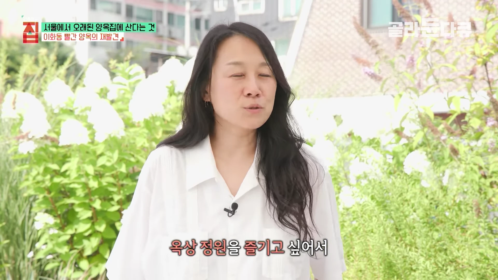 흰 셔츠를 입은 여성이 옥상 정원에서 인터뷰하고 있으며 화면 하단에는 '옥상 정원을 즐기고 싶어서'라는 자막이 있습니다.
