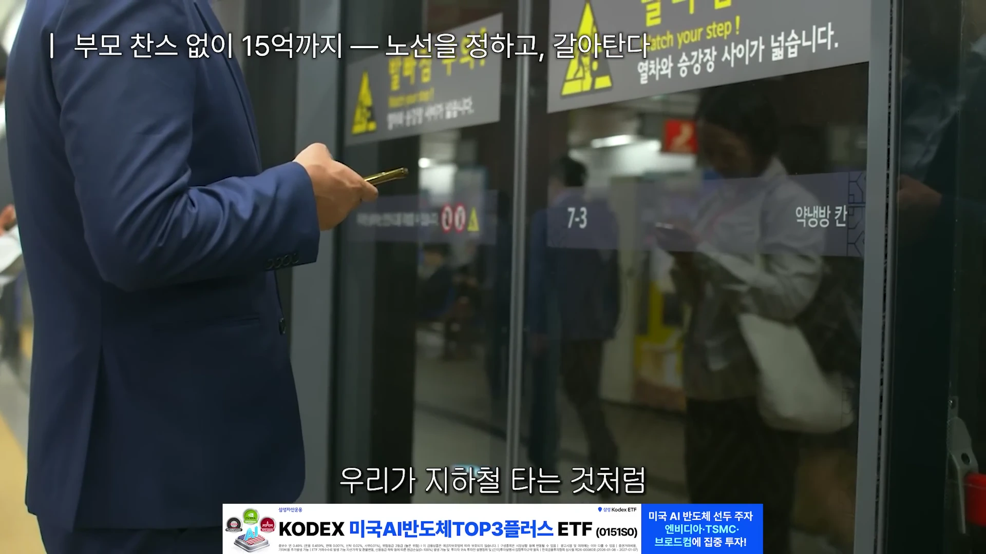 남색 정장을 입은 사람이 스마트폰을 보며 지하철 승강장에서 열차를 기다리는 모습과 그 위에 자막이 겹쳐진 영상 화면