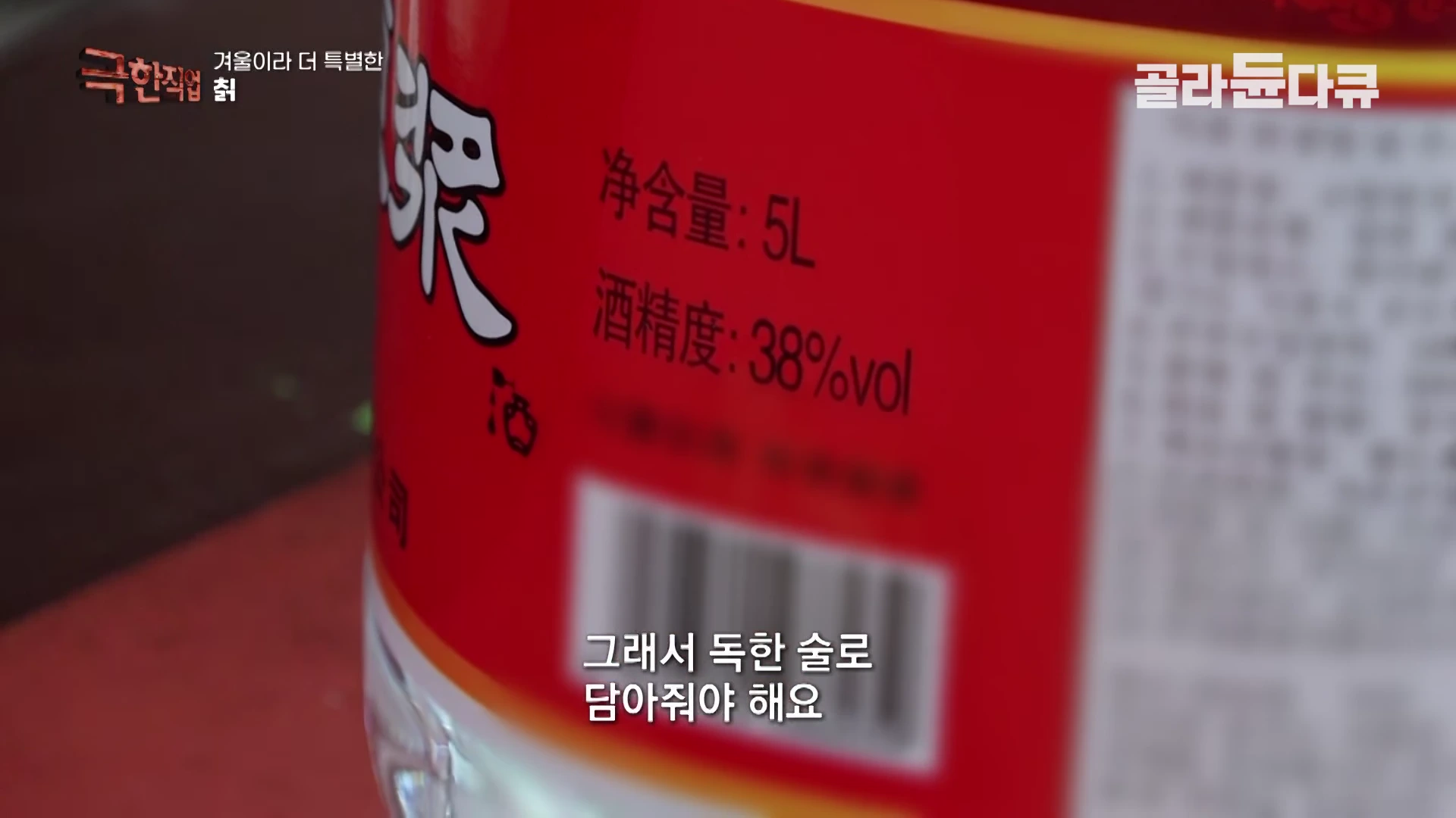 5리터 용량의 붉은색 술통 표면에 38% 도수가 적힌 라벨이 클로즈업되어 있으며 하단에는 '그래서 독한 술로 담아줘야 해요'라는 자막이 보입니다.