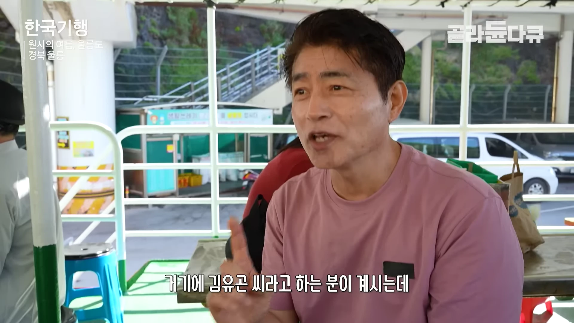 배에 탑승한 남성이 카메라를 향해 손가락으로 가리키며 이야기를 하고 있는 모습.