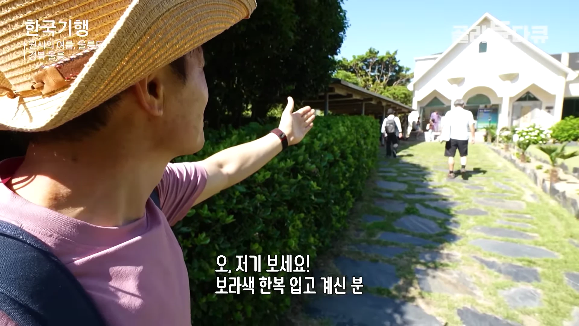 밀짚모자를 쓴 남성이 손을 뻗어 정원 너머의 사람들을 가리키고 있으며, 화면 중앙 하단에는 '오, 저기 보세요! 보라색 한복 입고 계신 분'이라는 자막이 떠 있습니다.