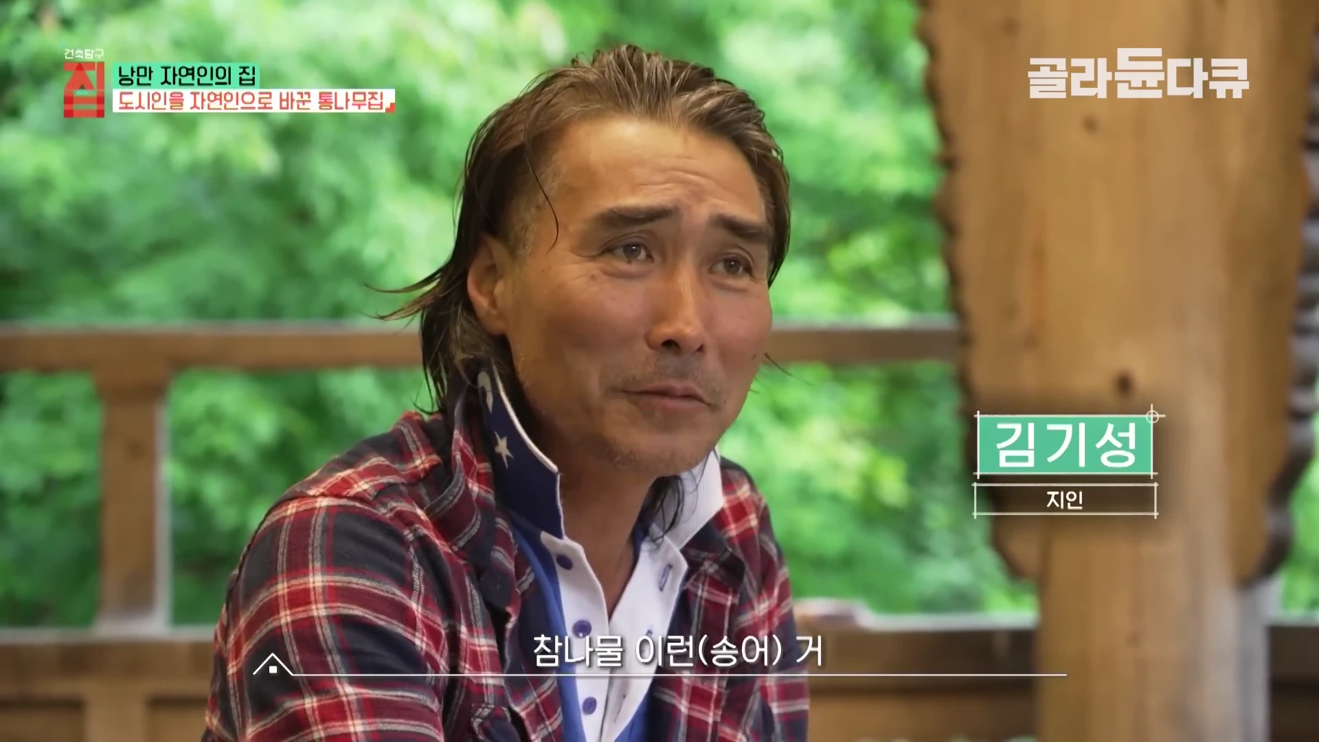 붉은색 체크무늬 셔츠를 입고 자연 속 야외 공간에 앉아 있는 중년 남성의 모습이 담긴 인터뷰 화면.