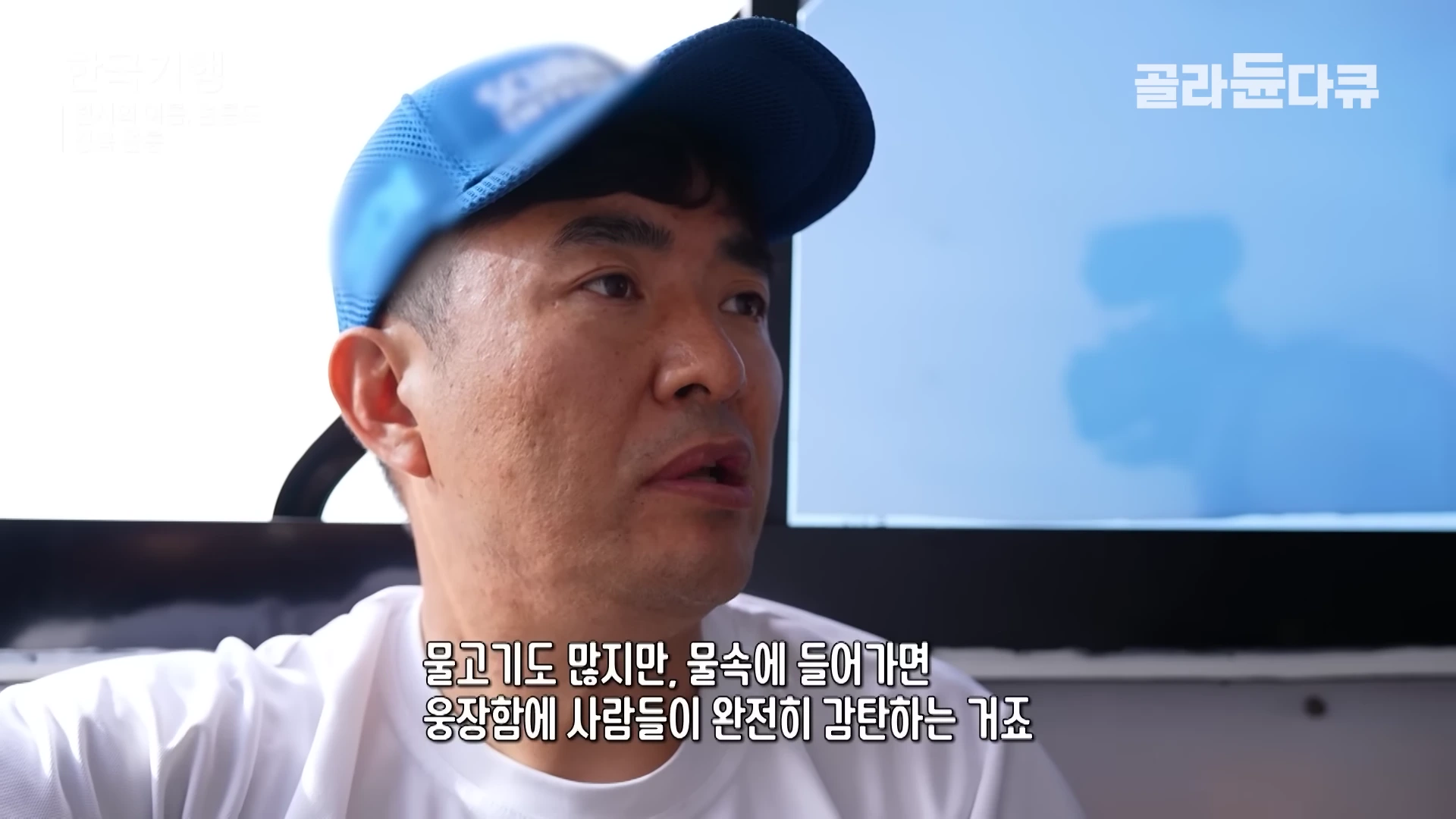 파란색 야구 모자를 쓴 중년 남성이 실내에서 정면을 바라보며 무언가 설명하고 있는 모습입니다. 화면 하단에는 인터뷰 내용이 자막으로 적혀 있습니다.