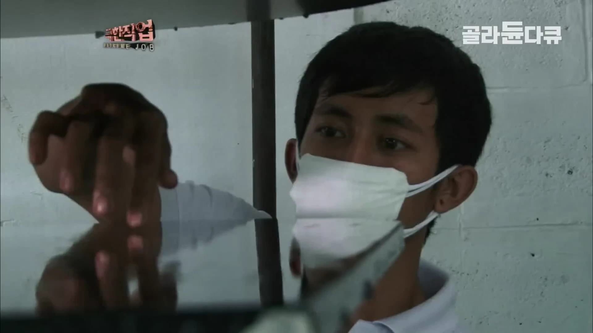 흰 마스크를 쓴 남성이 맨손으로 피아노 본체의 도장 상태를 정밀하게 확인하고 있는 모습.