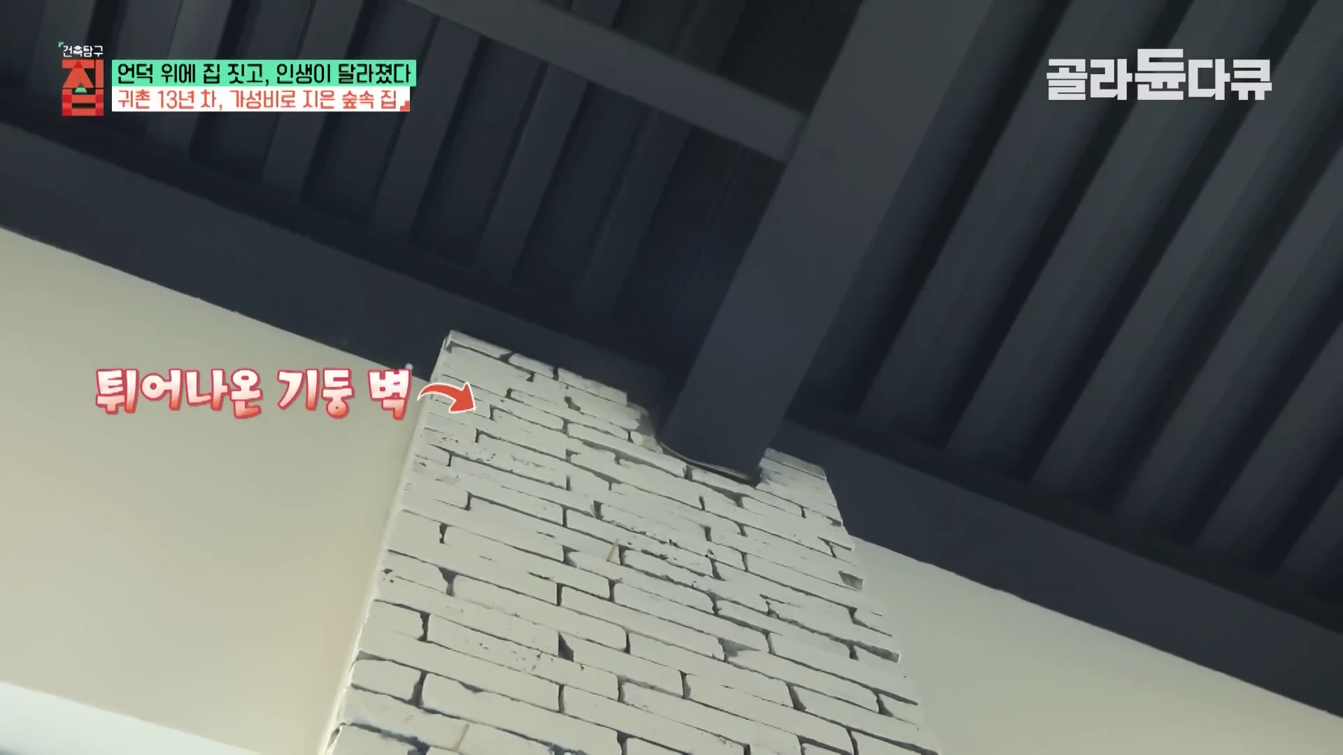 실내 천장과 맞닿은 벽면 일부가 돌출되어 있으며, 그 위에 '튀어나온 기둥 벽'이라는 한글 자막과 화살표가 표시된 영상 화면.