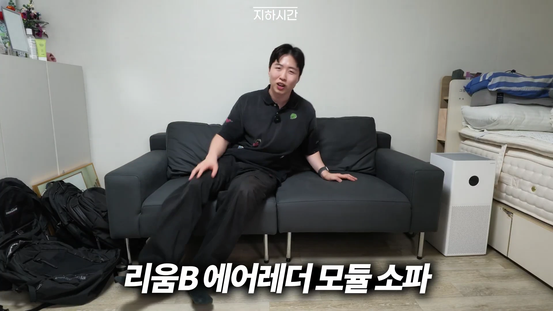 실내에서 검은색 모듈 소파에 앉아 있는 남성이 카메라를 보며 이야기를 나누고 있다. 하단에는 리움B 에어레더 모듈 소파라는 자막이 표시되어 있다.