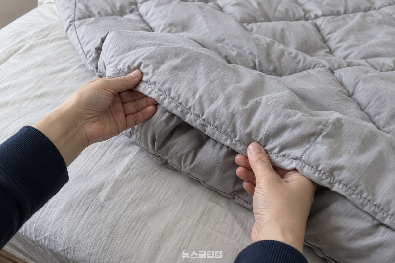 가을 이불의 가장자리와 봉제선을 살펴보는 모습 / 기사 이해를 돕기 위한 생성형 이미지