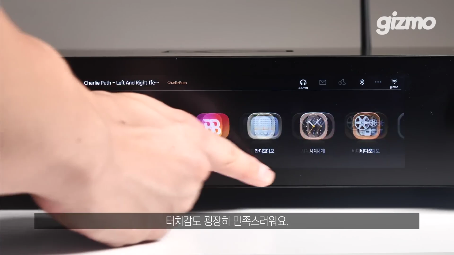 사람의 손이 하이파이로즈 RS451 오디오 기기의 가로로 긴 전면 LCD 터치스크린을 조작하는 모습.