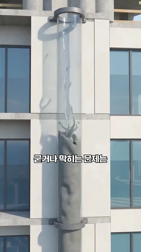 건물 외벽에 부착된 투명한 수직 관 안으로 콘크리트가 아래에서 위로 솟구쳐 오르는 모습을 보여주는 그래픽 이미지