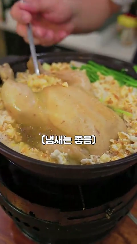 진한 육수에 푹 삶아진 통닭 주변으로 팝콘이 가득 올려져 있고 숟가락으로 닭고기를 뜨고 있는 모습