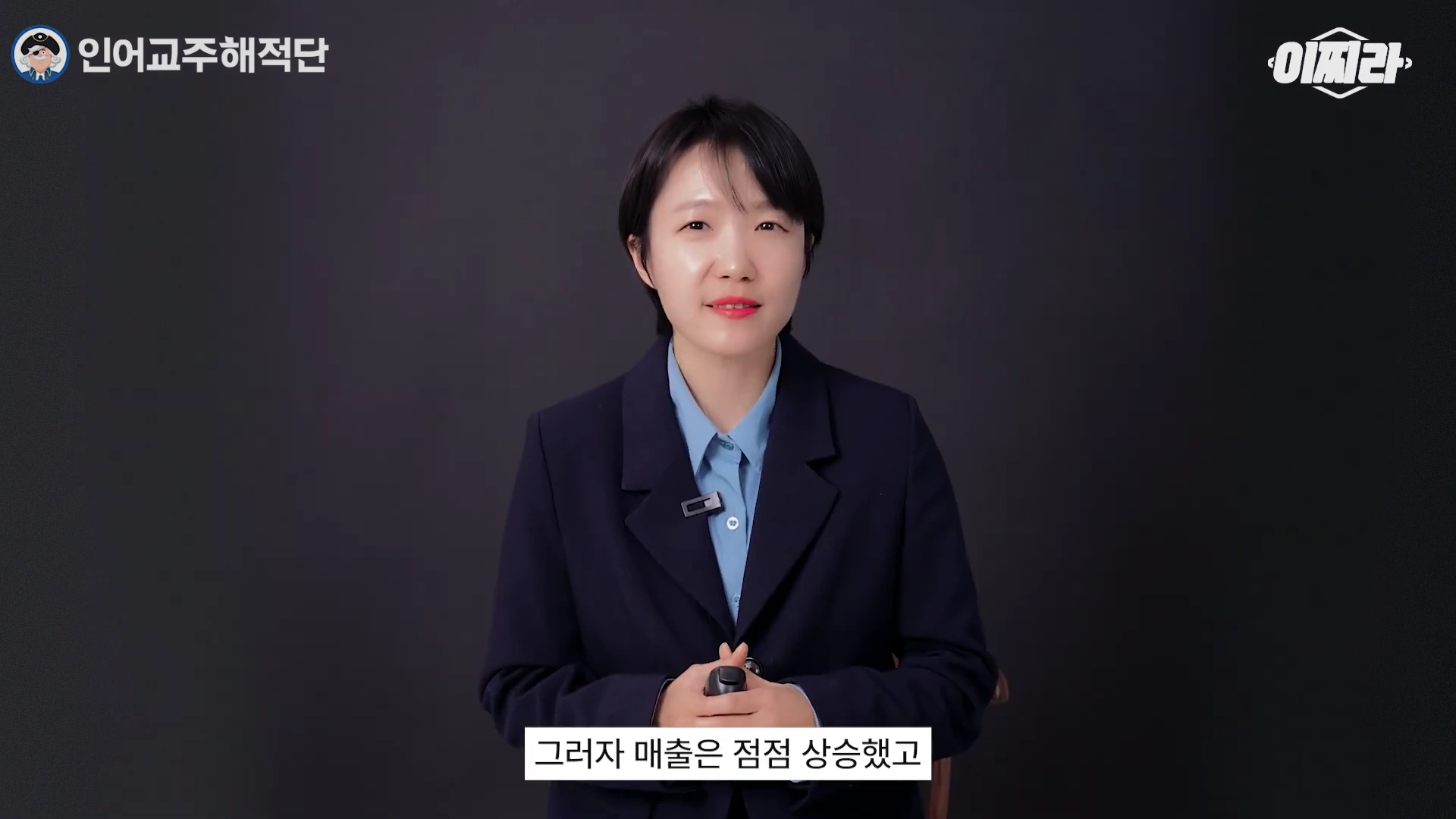 단정한 검정 재킷에 셔츠를 입은 여성이 화면을 바라보며 이야기하고 있으며, 아래쪽에 자막이 있는 영상 프레임입니다.