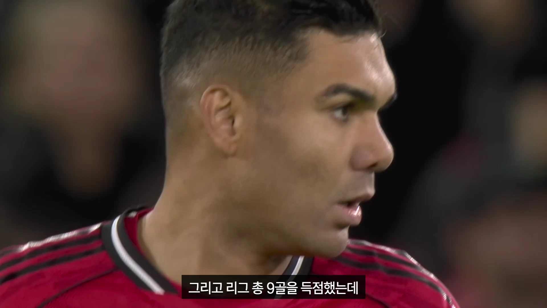 축구 경기장에서 옆을 바라보고 있는 맨체스터 유나이티드 유니폼을 입은 카세미루의 옆모습, 화면 하단에는 리그 득점 기록에 관한 한국어 자막이 표시되어 있습니다.