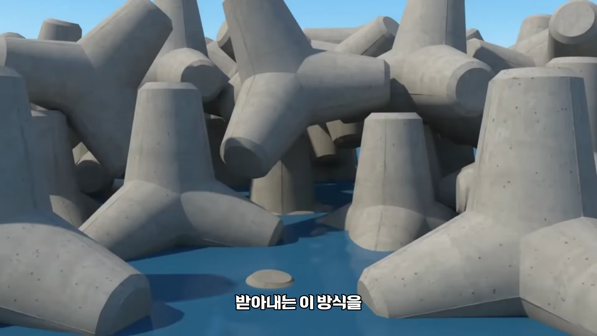 바다 위에 엉켜 쌓여 있는 여러 개의 회색 테트라포드 콘크리트 블록들