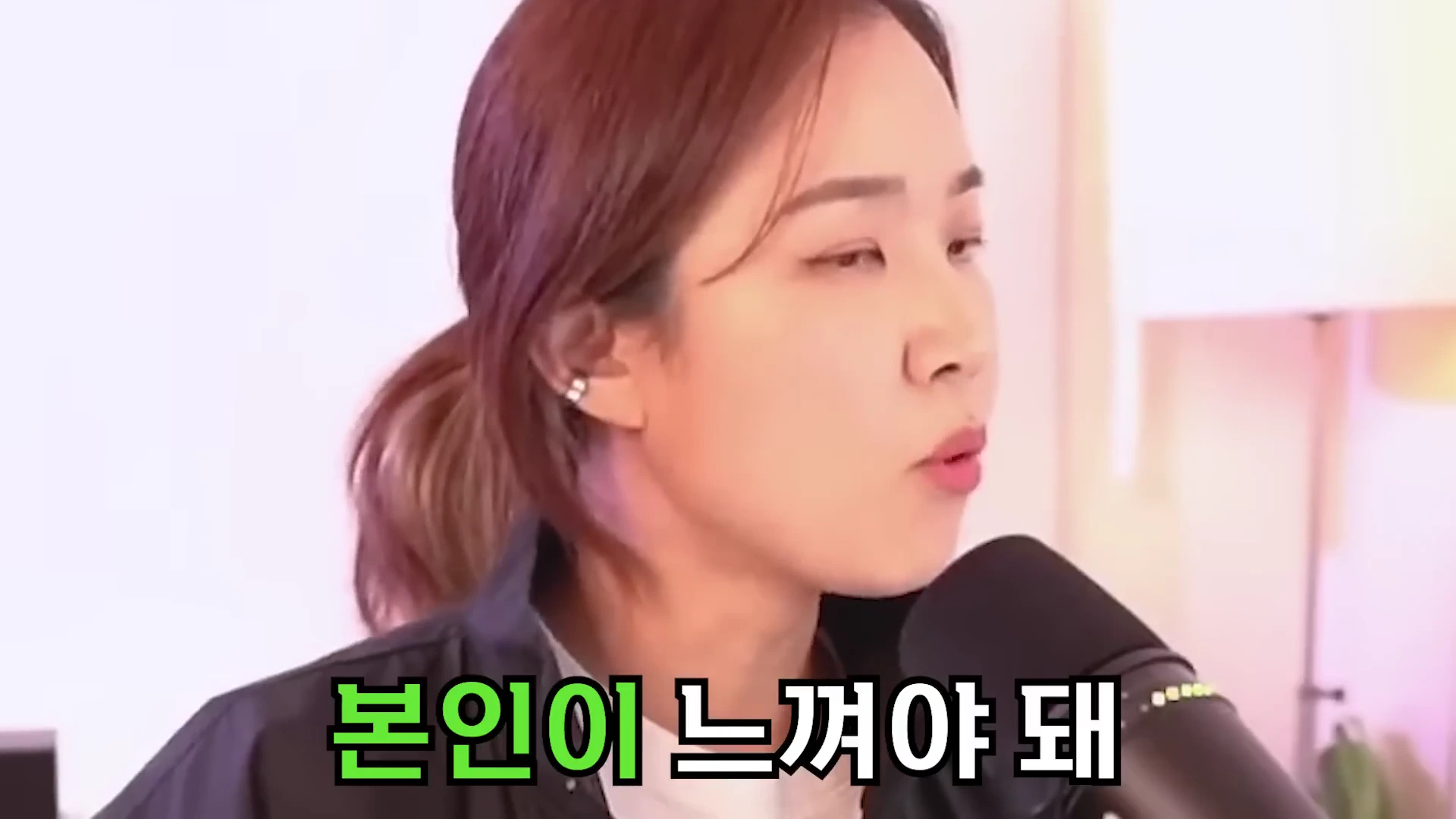 한 여성이 마이크 앞에서 진지한 표정으로 이야기하고 있는 모습. 화면 하단에는 녹색과 흰색 글씨로 '본인이 느껴야 돼'라는 자막이 강조되어 있다.