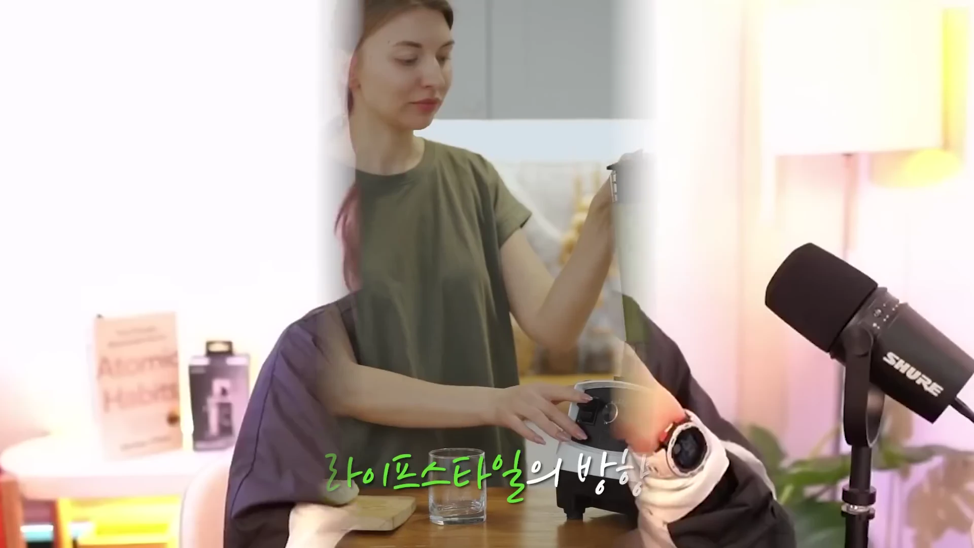 실내에서 올리브색 티셔츠를 입은 여성이 믹서기를 조작하고 있으며, 앞쪽에는 마이크와 함께 '라이프스타일의 방향'이라는 자막이 떠 있습니다.