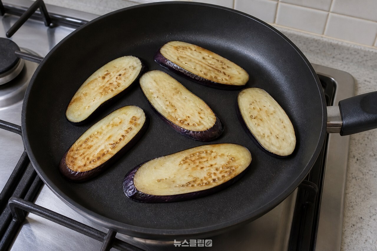 기름을 두르지 않은 팬에서 노릇하게 굽는 가지 / 기사 이해를 돕기 위한 생성형 이미지