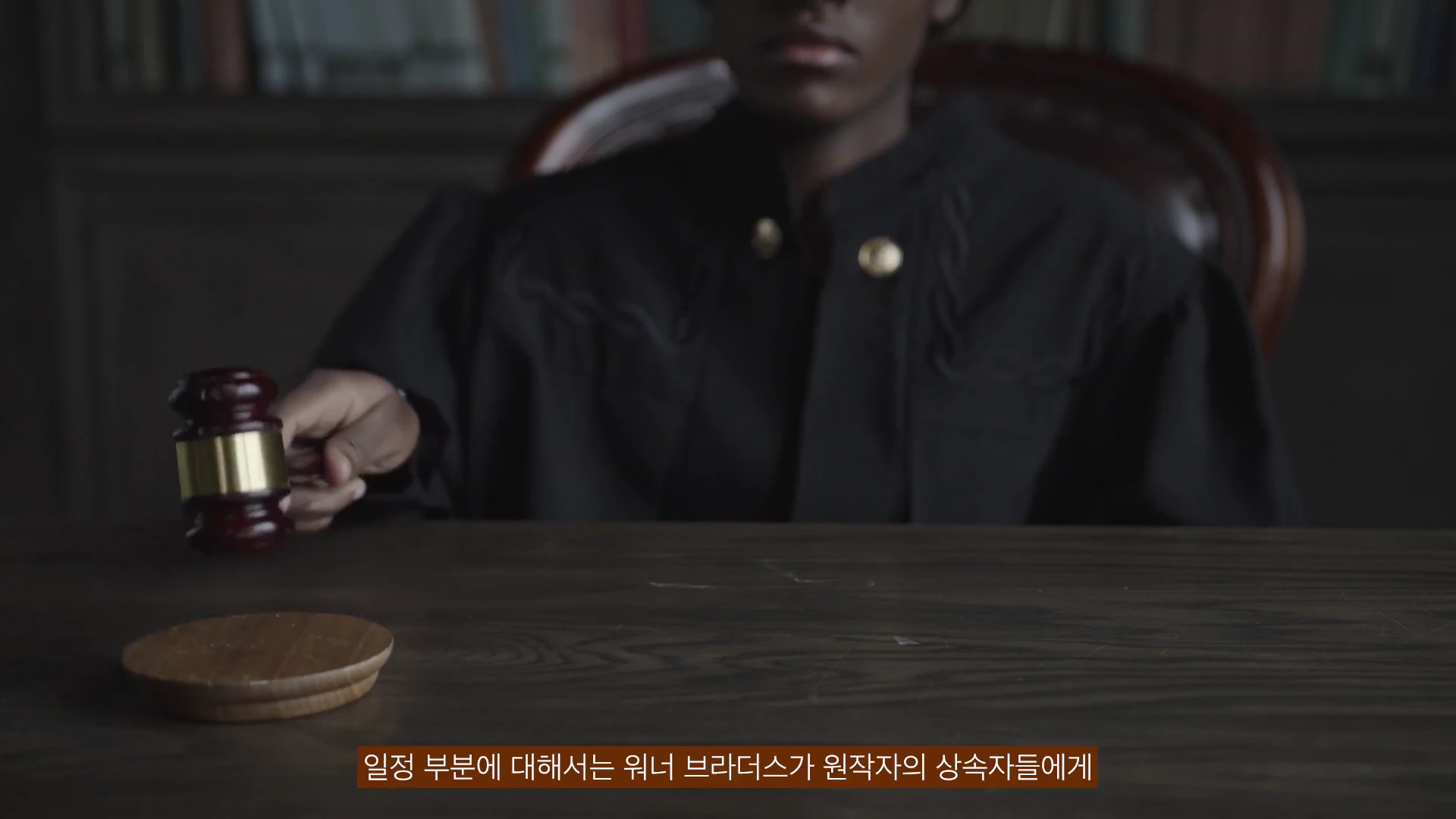 법복을 입은 사람이 나무 탁자 위에서 판사봉을 두드리고 있는 모습
