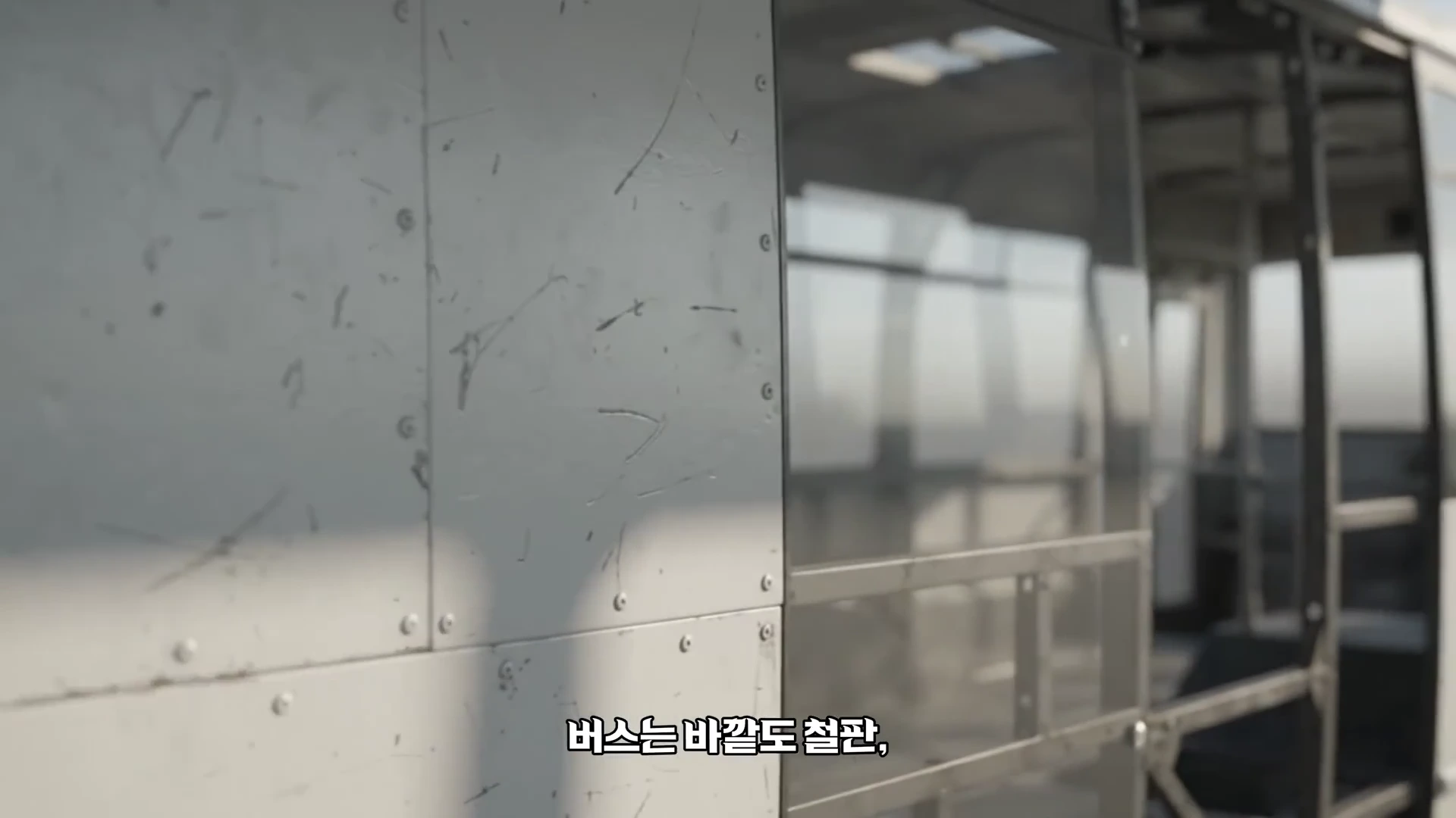 폐차된 버스의 내부가 드러나 있는 모습으로, 나사로 고정된 철제 외벽 패널과 빈 뼈대 구조가 근접 촬영되어 있다.
