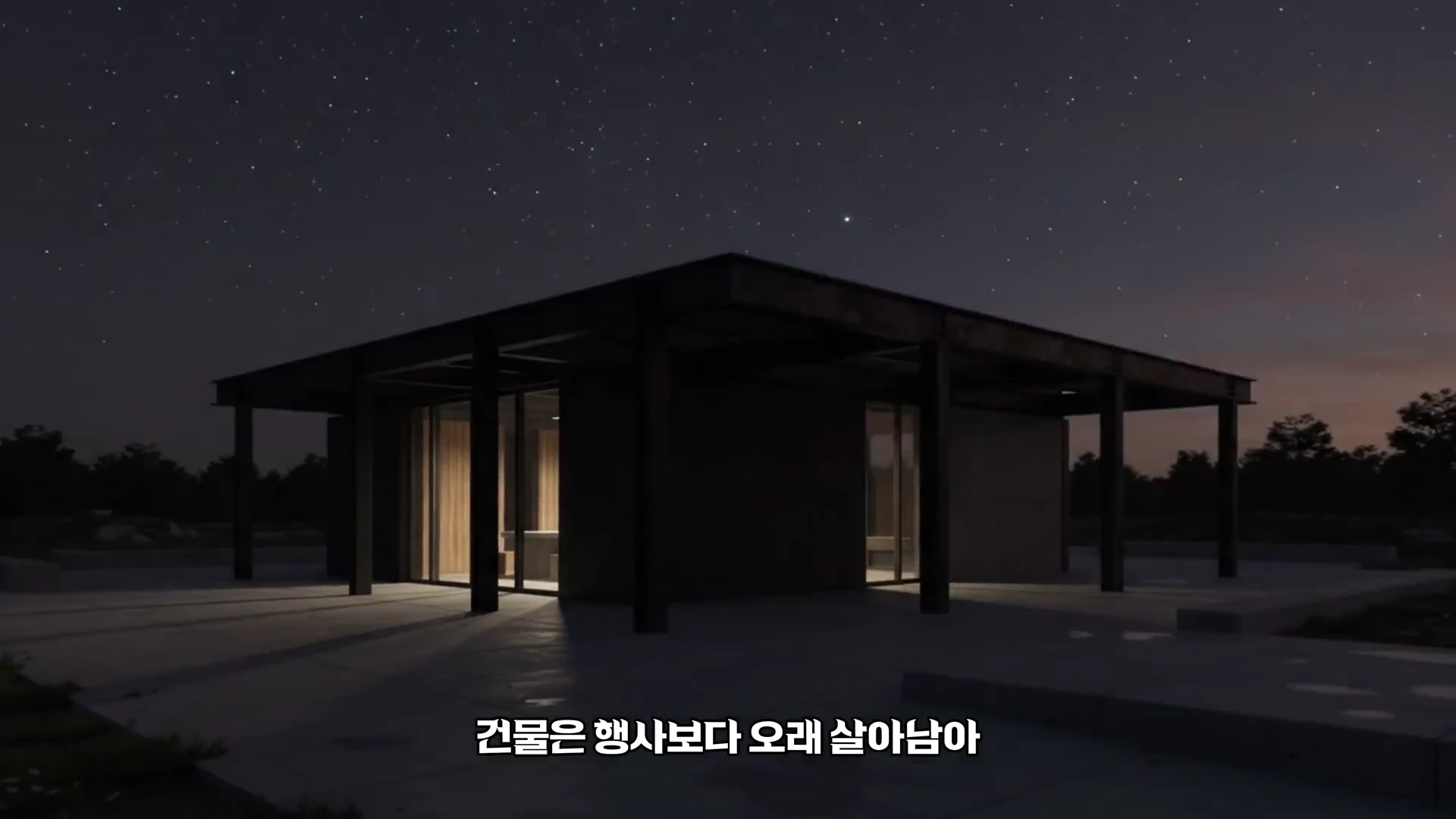 어두운 밤하늘 아래 조명이 켜진 현대적인 건축물이 서 있고 하단에는 '건물은 행사보다 오래 살아남아'라는 자막이 표시되어 있습니다.