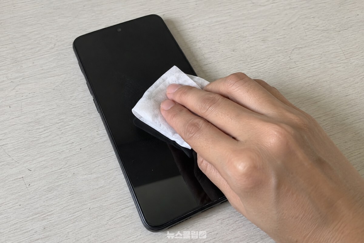 휴대전화 액정을 물티슈로 닦는 모습 / 기사 이해를 돕기 위한 생성형 이미지
