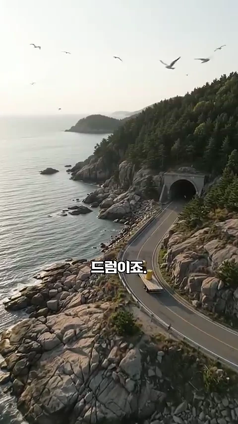 바닷가 절벽을 따라 난 해안 도로를 달리는 트럭이 노란색 드럼통을 싣고 터널로 들어가는 모습을 담은 항공 촬영 영상 캡처 화면입니다.
