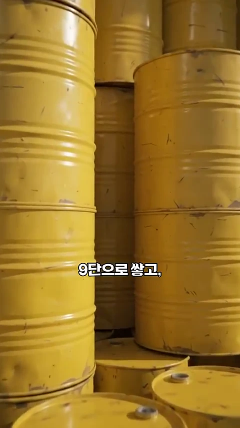 노란색 원통형 드럼통들이 여러 층으로 빽빽하게 쌓여 있는 모습이 담긴 영상 캡처 화면입니다.