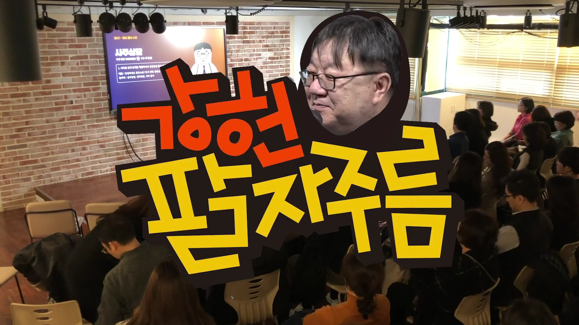 강연장에서 안경을 쓴 남성이 발표하고 있고, 앞쪽에 앉아 있는 청중들의 뒷모습이 보인다. 화면에는 '강헌의 팔자주름'이라는 큰 제목이 노란색과 붉은색 글씨로 합성되어 있다.