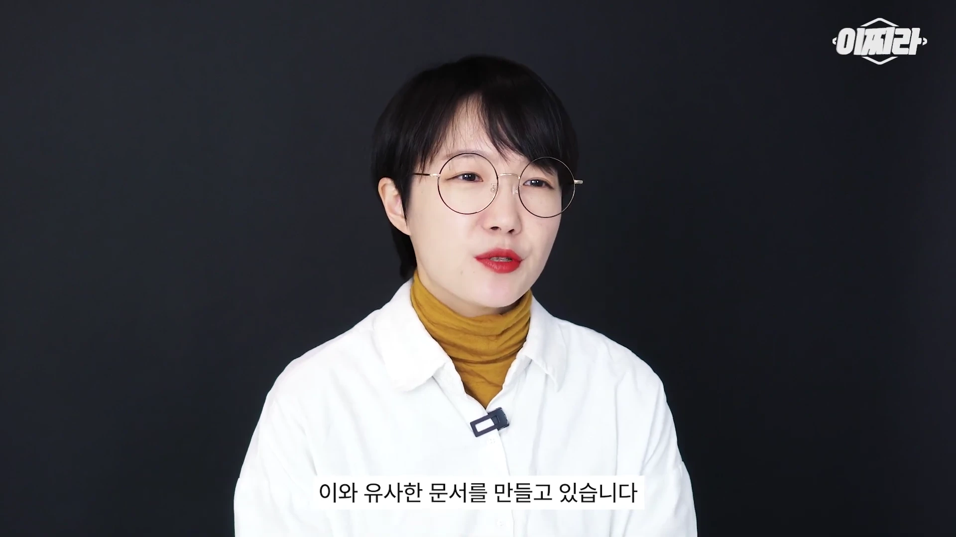 안경을 쓴 단발머리의 여성 출연자가 검은색 배경 앞에서 정면을 응시하며 이야기하고 있고, 화면 하단에는 자막이 떠 있습니다.