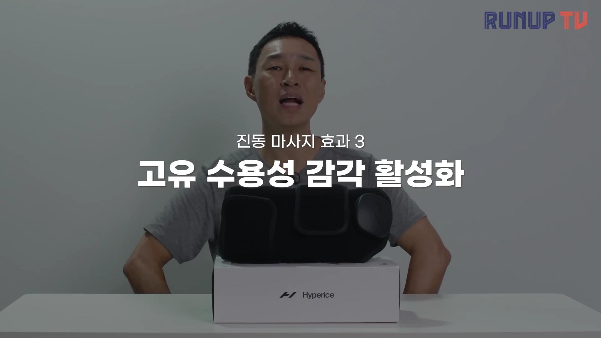 실내 스튜디오에서 한 남성이 '진동 마사지 효과 3 고유 수용성 감각 활성화'라는 자막이 띄워진 영상 속에서 무릎 보호대 제품을 앞에 두고 설명하고 있다.