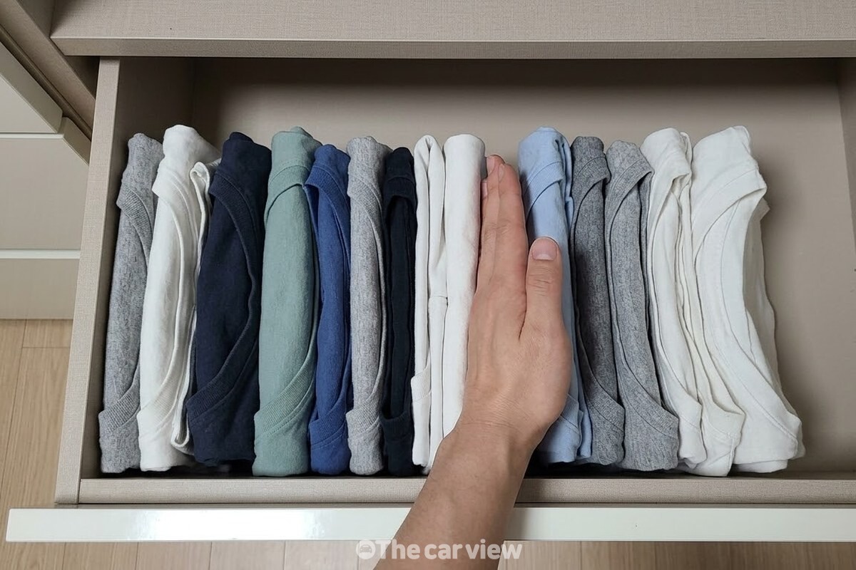 세워서 꽂은 여름옷 사이에 손바닥을 넣어 옆으로 밀어 보며 채운 정도를 확인한다. / 기사 이해를 돕기 위한 생성형 이미지