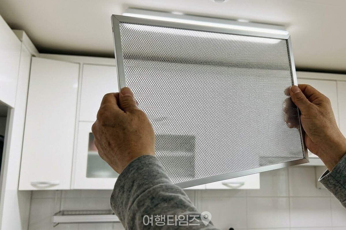 떼어 낸 은색 후드 필터를 손으로 들어 천장등 불빛에 비춰 그물망을 살펴보는 모습. / 기사 이해를 돕기 위한 생성형 이미지